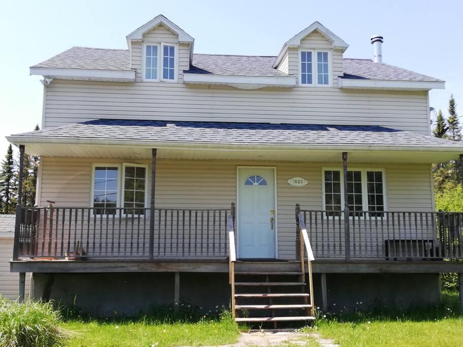 ein weißes Haus mit einer Veranda und einer Treppe in der Unterkunft Quiet place in the heart of Laurentides in Sainte-Lucie-de-Doncaster