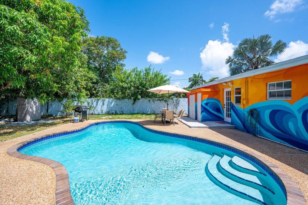 a swimming pool in front of a house at Casa Ola - Surf Themed Pool Home, Near Downtown in Fort Lauderdale