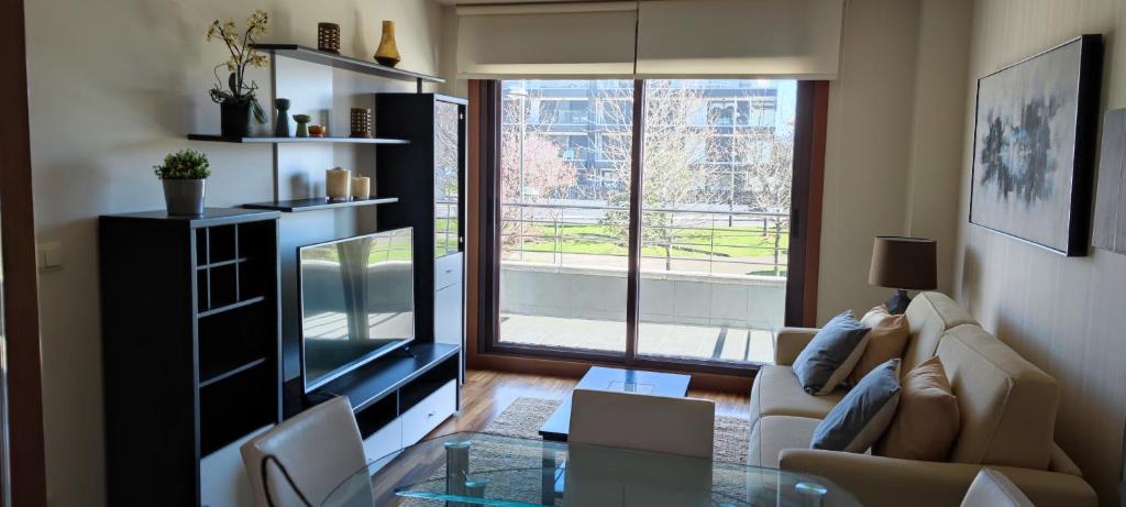 a living room with a tv and a glass table at Acogedor apartamento con terraza en Portonovo in Portonovo