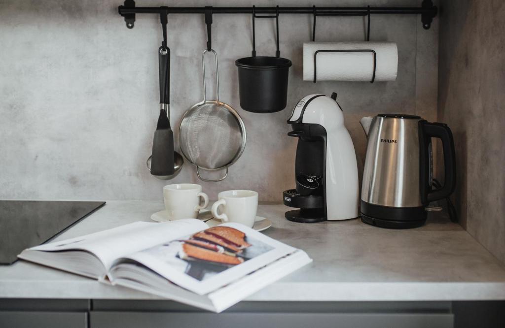 a kitchen counter with a book and a sandwich and cups at Rozenstein design residence in Brocēni