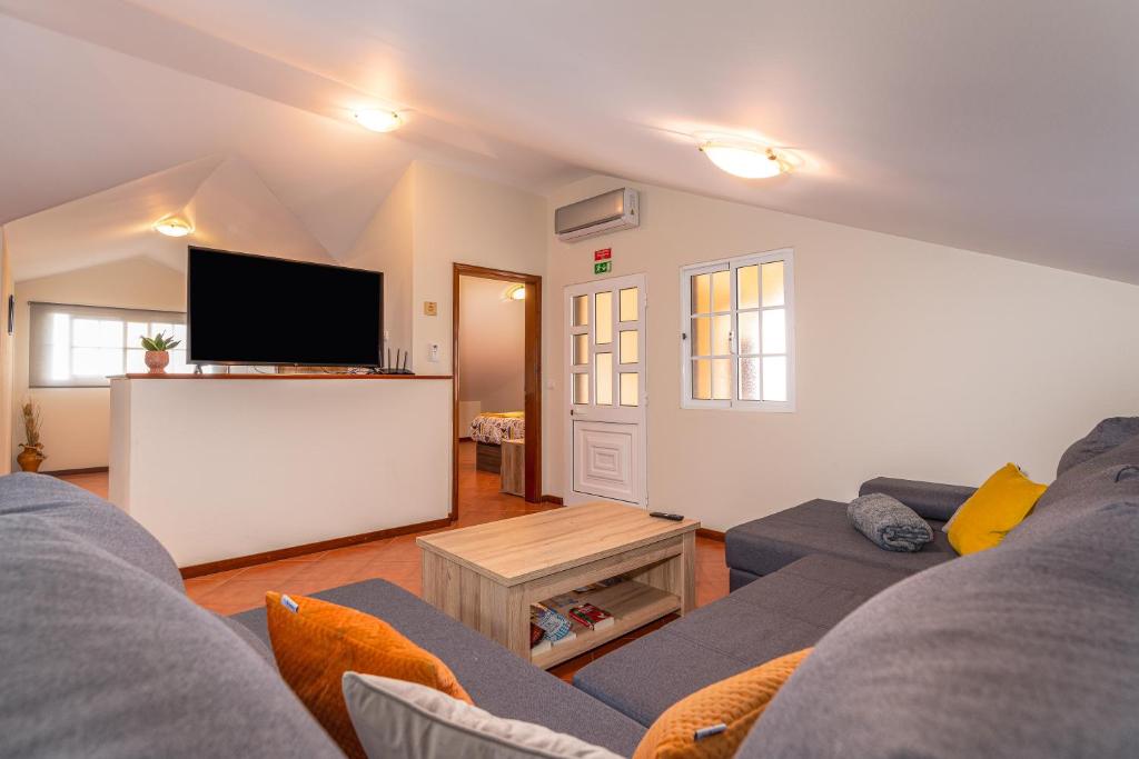 a living room with a couch and a flat screen tv at CASA POR DO SOL in Calheta