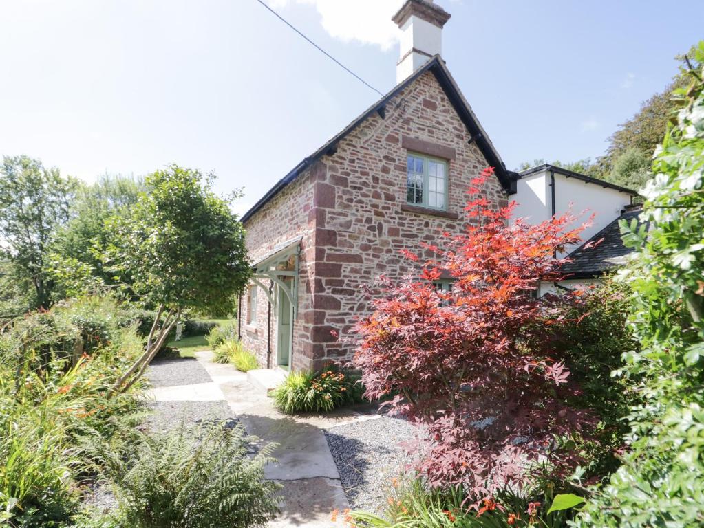 a brick house with a garden in front of it at Caldhu Cottage in Holmrook