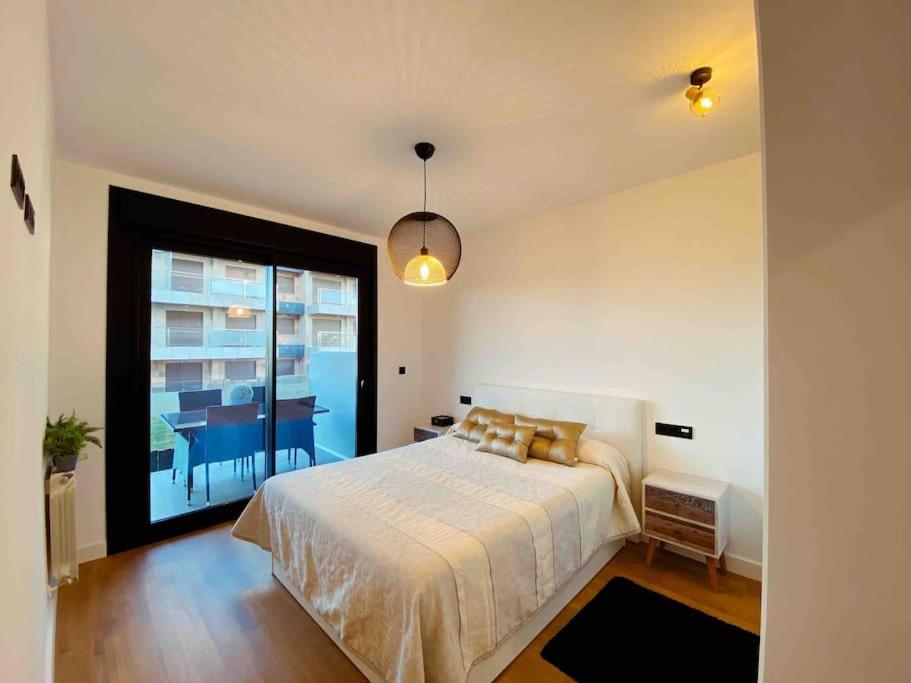ein Schlafzimmer mit einem Bett und einem großen Fenster in der Unterkunft Apartamento en Edificio Nuevo con Piscina in Portonovo