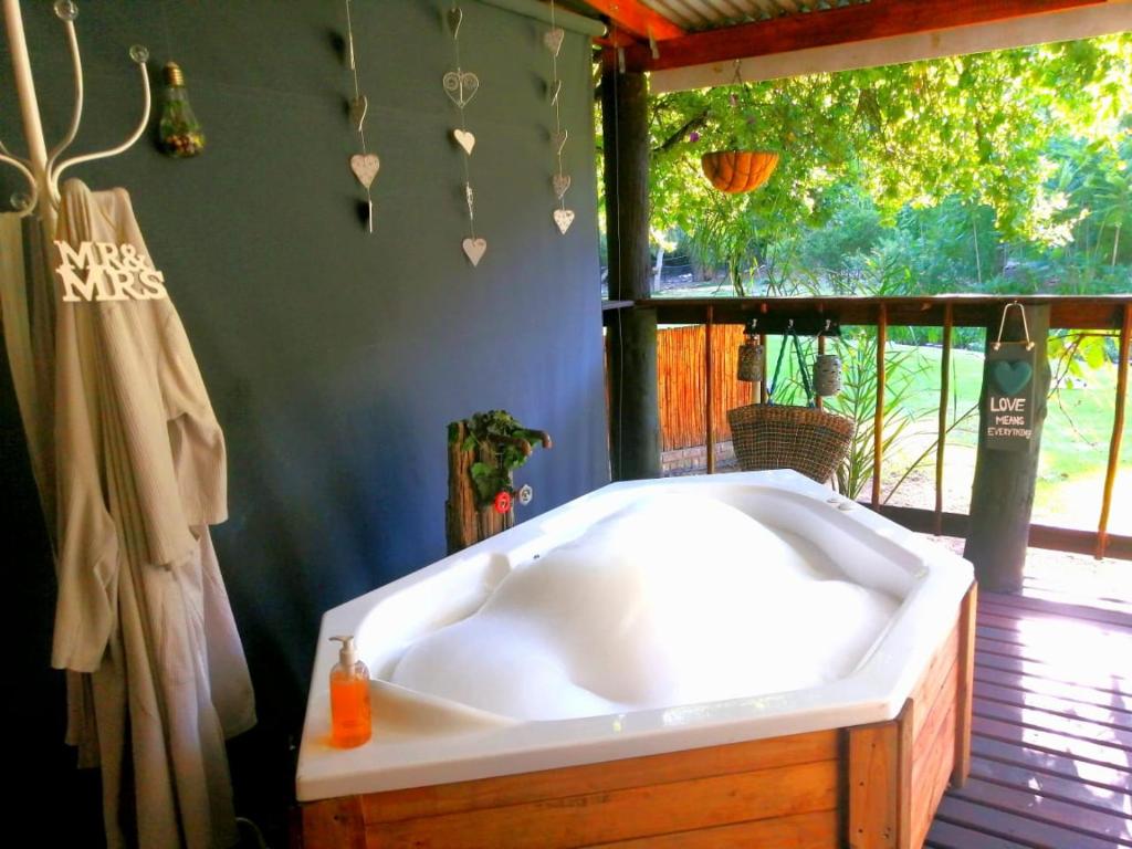 a large bath tub in a bathroom with a window at Cango Retreat Lover's nest in Oudtshoorn