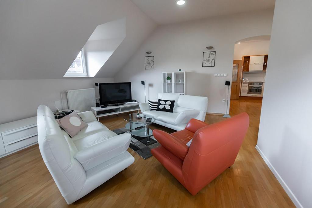 Una sala de estar con muebles blancos y un televisor. en Suzana Iron's apartment, en Liubliana