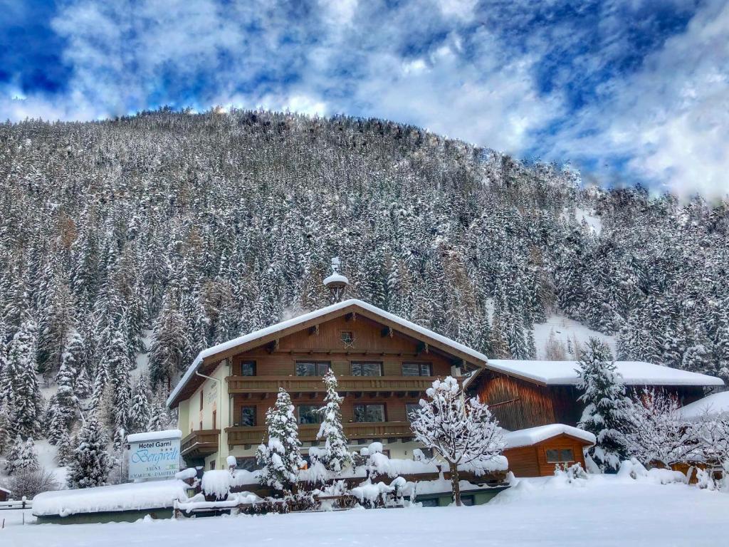 a log cabin in the snow with a mountain at Hotel Garni Bergwelt in Sankt Anton am Arlberg