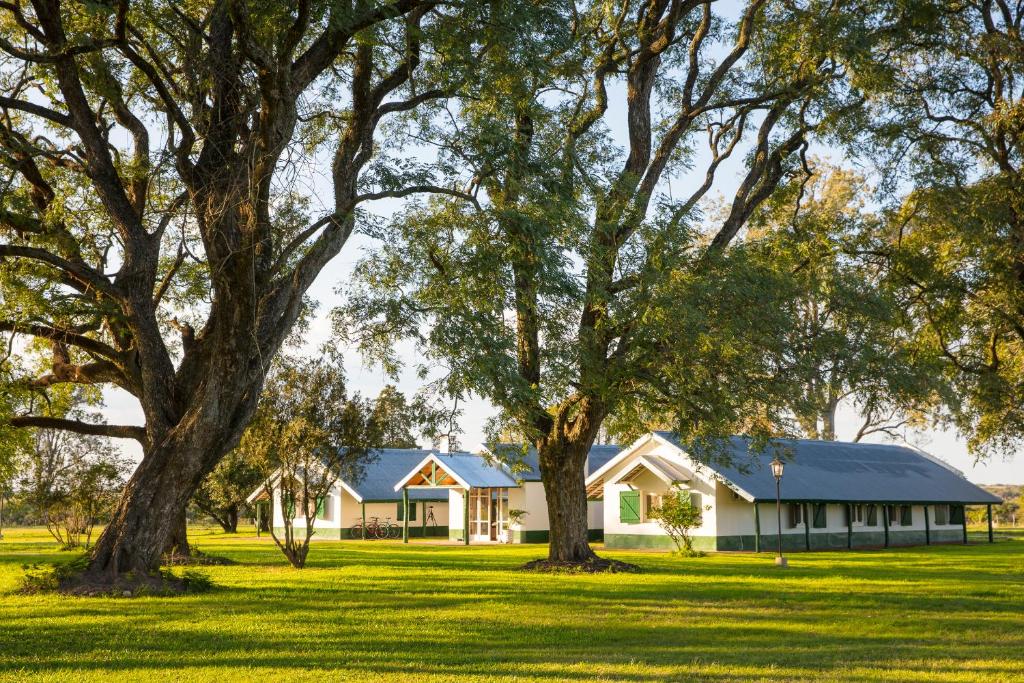 a house in the middle of a field with trees at Estancia San Agustin in Curuzú Cuatiá