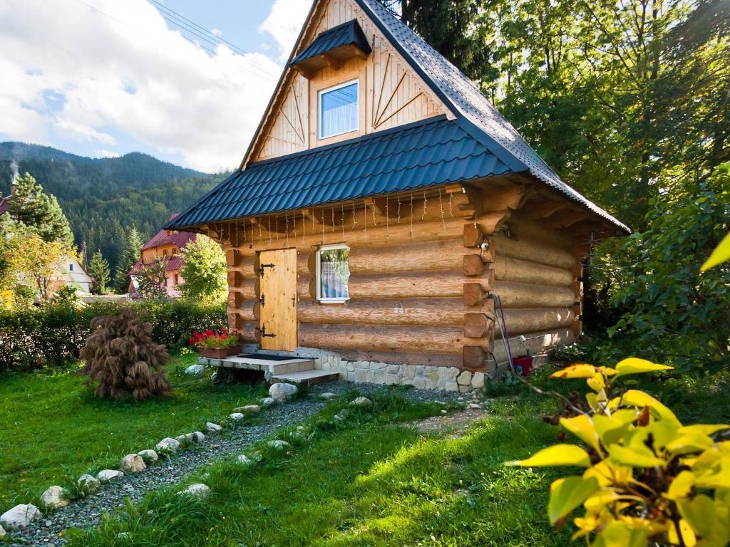 a log cabin with a bench in the grass at Domki u Ciaptoka in Zakopane