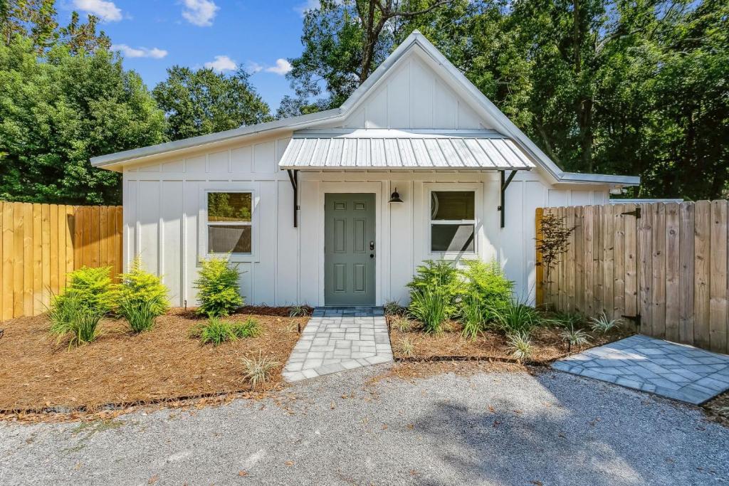 uma garagem branca com uma porta verde e uma cerca em Peach's Place em Pensacola