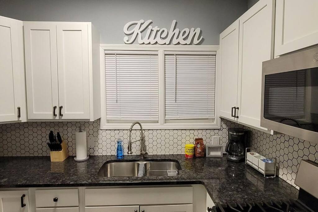 a kitchen with a sink and a kitchen sign on the wall at Retreat Suite 1 - Cozy Downtown Getaway in Grand Rapids