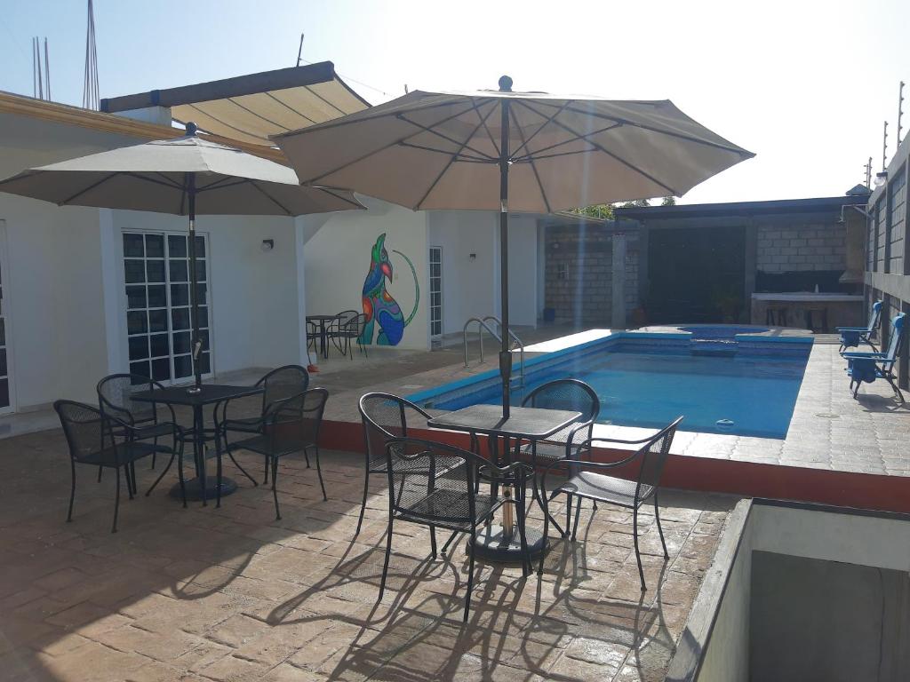 - deux tables et chaises avec parasols à côté de la piscine dans l'établissement HB Alebrijes SC, à Lachiraguigú