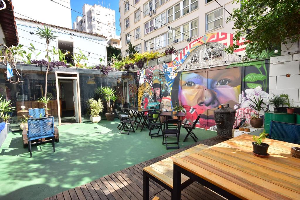 a patio with tables and chairs and a mural at Aurora Hostel Rio in Rio de Janeiro