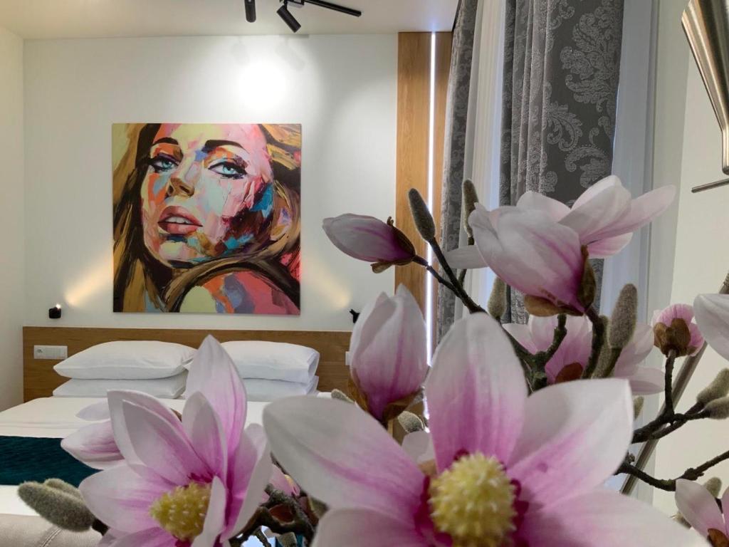 a bedroom with a painting of a man with pink flowers at Apartment z kominkiem w sercu Wrocławia in Wrocław