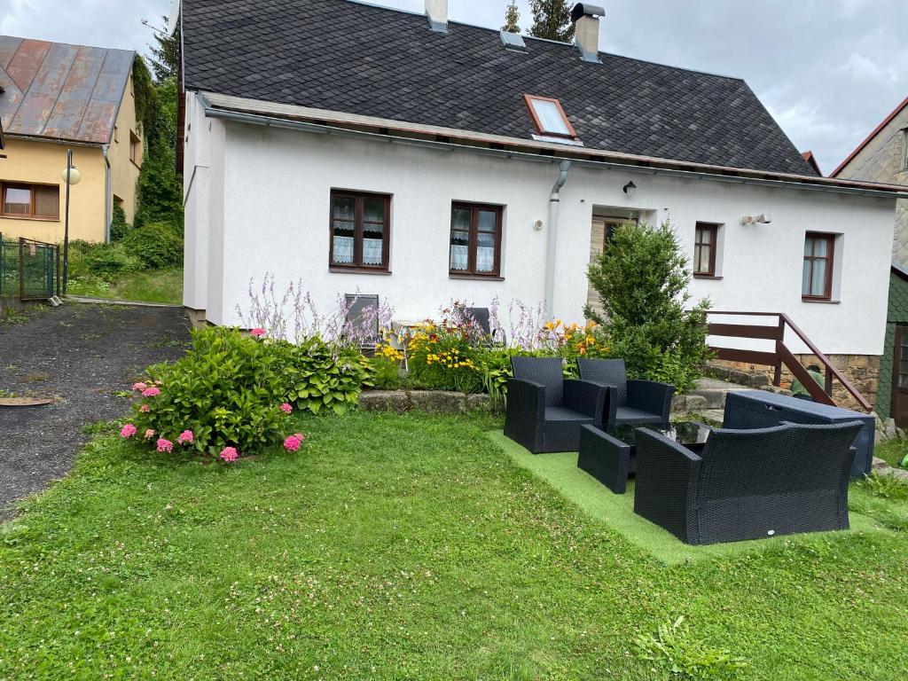 a white house with some chairs in the yard at rekreační dům Pohoda in Jiřetín pod Jedlovou