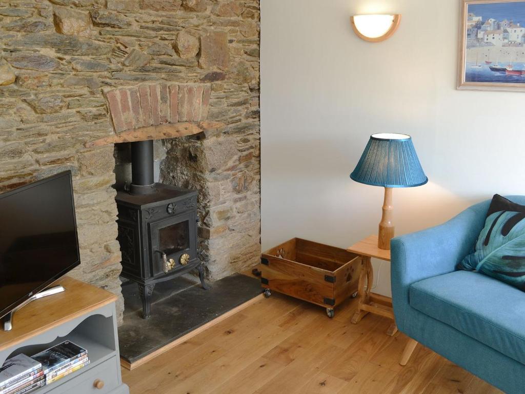 a living room with a stone fireplace and a blue couch at Duke Street in Lostwithiel
