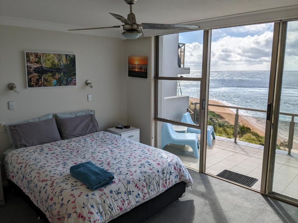 a bedroom with a bed and a view of the ocean at Toowoon Bay Beachfront Apartment in The Entrance