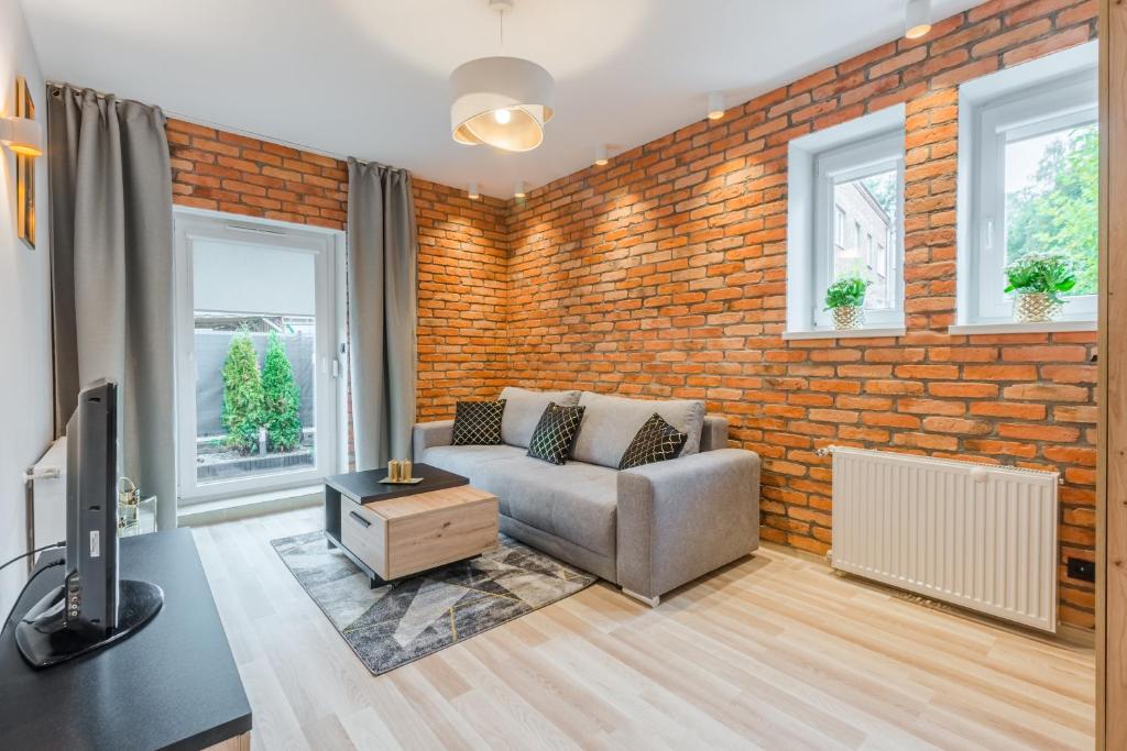 een woonkamer met een bank en een bakstenen muur bij Apartament Księżycowy Sopot in Sopot