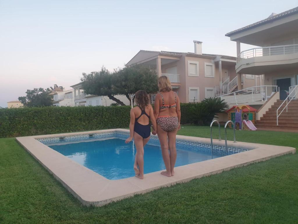 Playaにあるprimera línea de la playa de oliva con jardín y piscina.の二人の女性がプールの隣に立っている