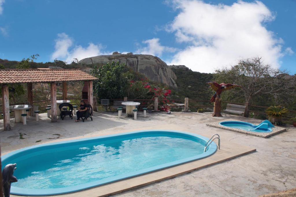 ein Schwimmbad in einem Garten mit einem Berg im Hintergrund in der Unterkunft Lá na Roça - Belezas do Monte Chalé, Suítes & Restaurante in Monte das Gameleiras