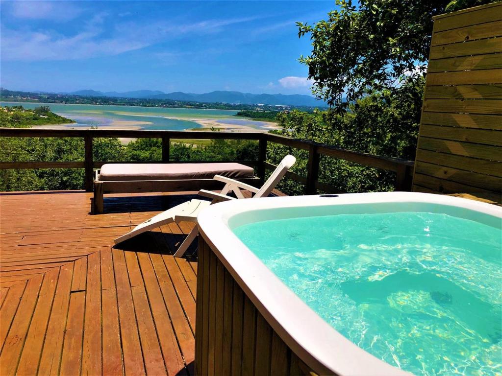 a hot tub on a deck with a view of the water at Chalés e Bangalôs Ibiraquera in Praia do Rosa