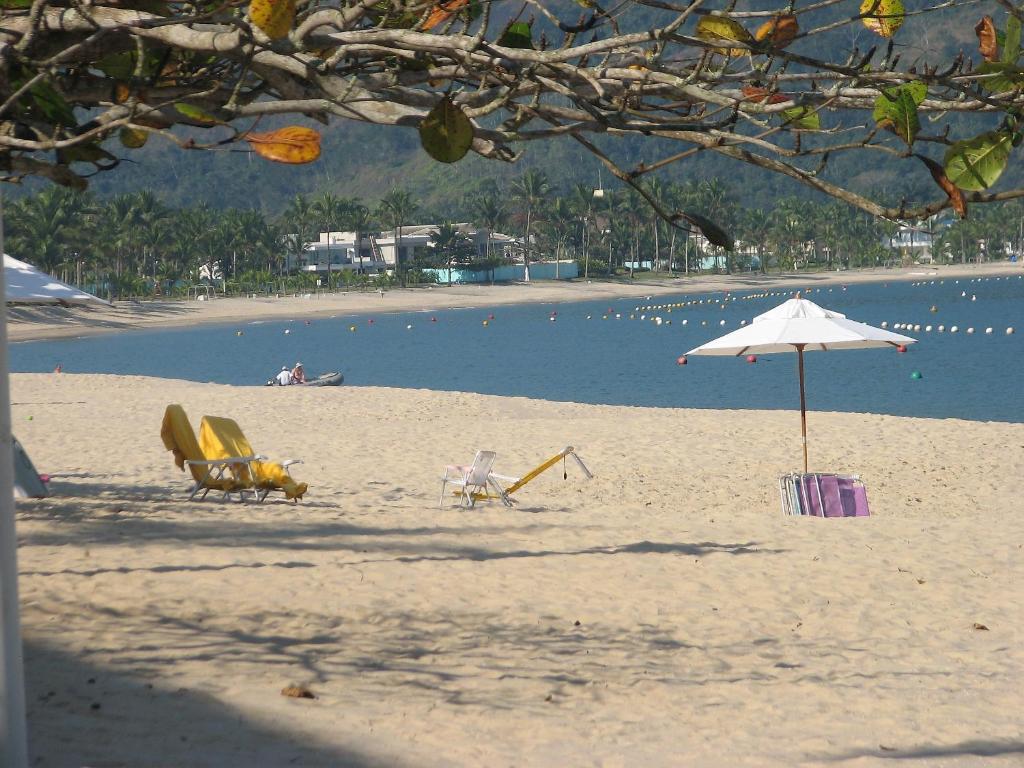 - une plage avec des chaises, un parasol et l'eau dans l'établissement Apartamento a 50m da areia - Praia da Tabatinga, à Caraguatatuba