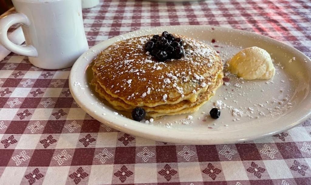 a plate of pancakes with blueberries on a table at Red Roof Inn & Suites Pigeon Forge Parkway in Pigeon Forge