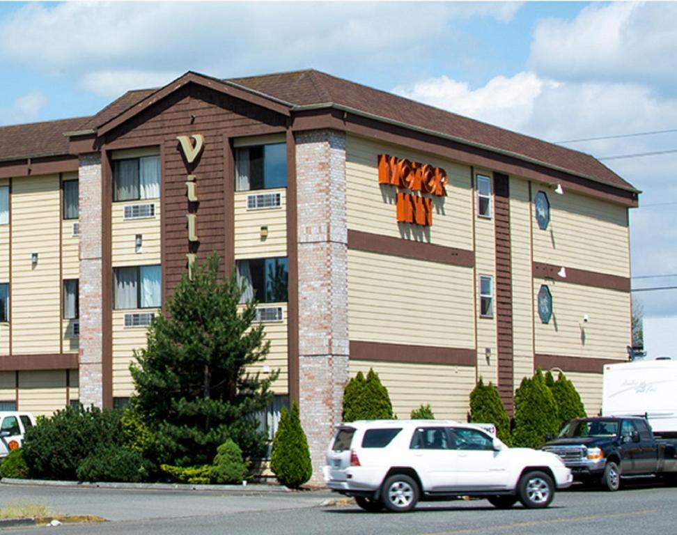 a building with a white car parked in front of it at Village Inn & Suites Marysville in Marysville