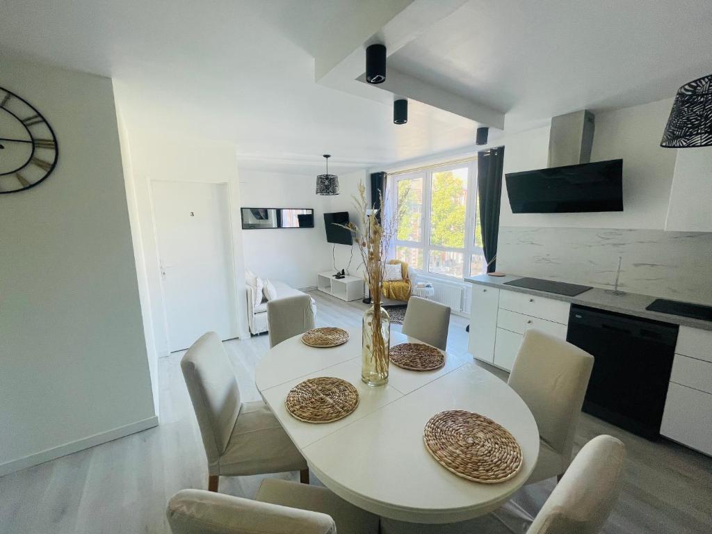 a white kitchen with a white table and chairs at Appartement Charmant Cocon Plus in Croix