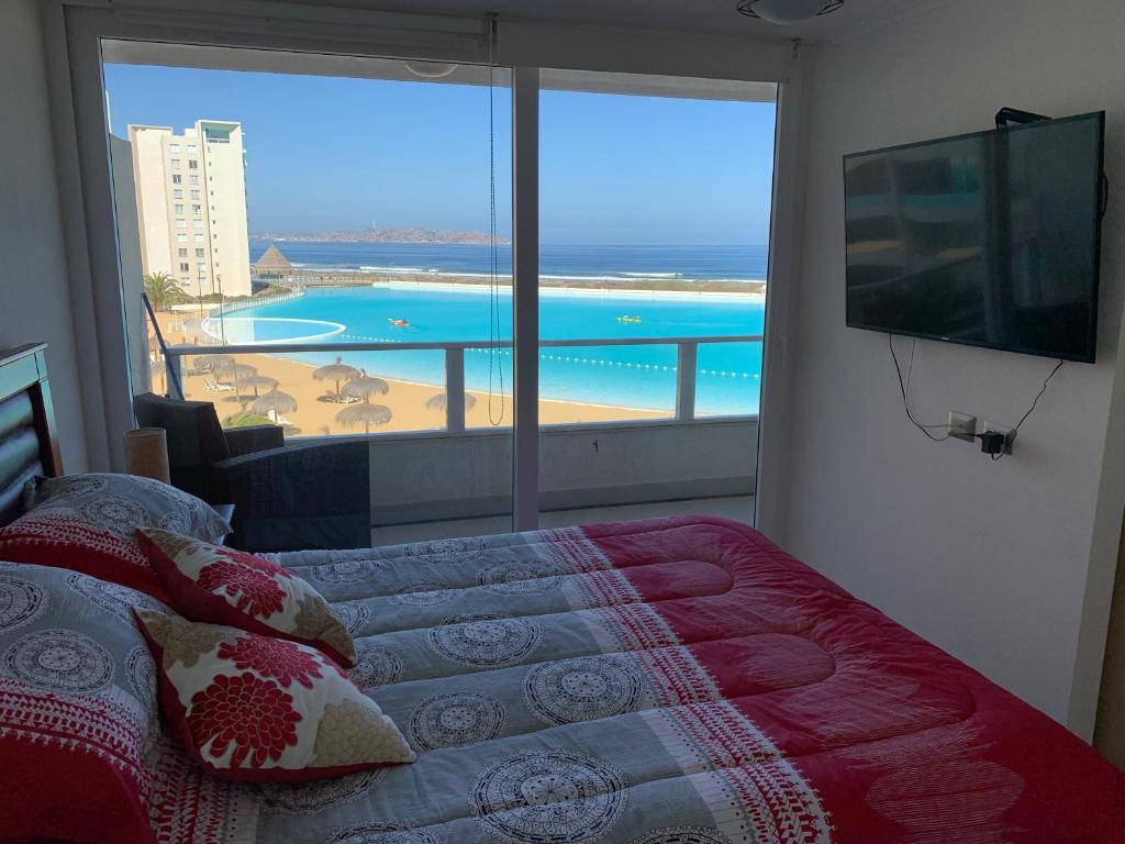 1 dormitorio con cama y vistas a la playa en DEPARTAMENTO EN RESORT LAGUNA DEL MAR en La Serena