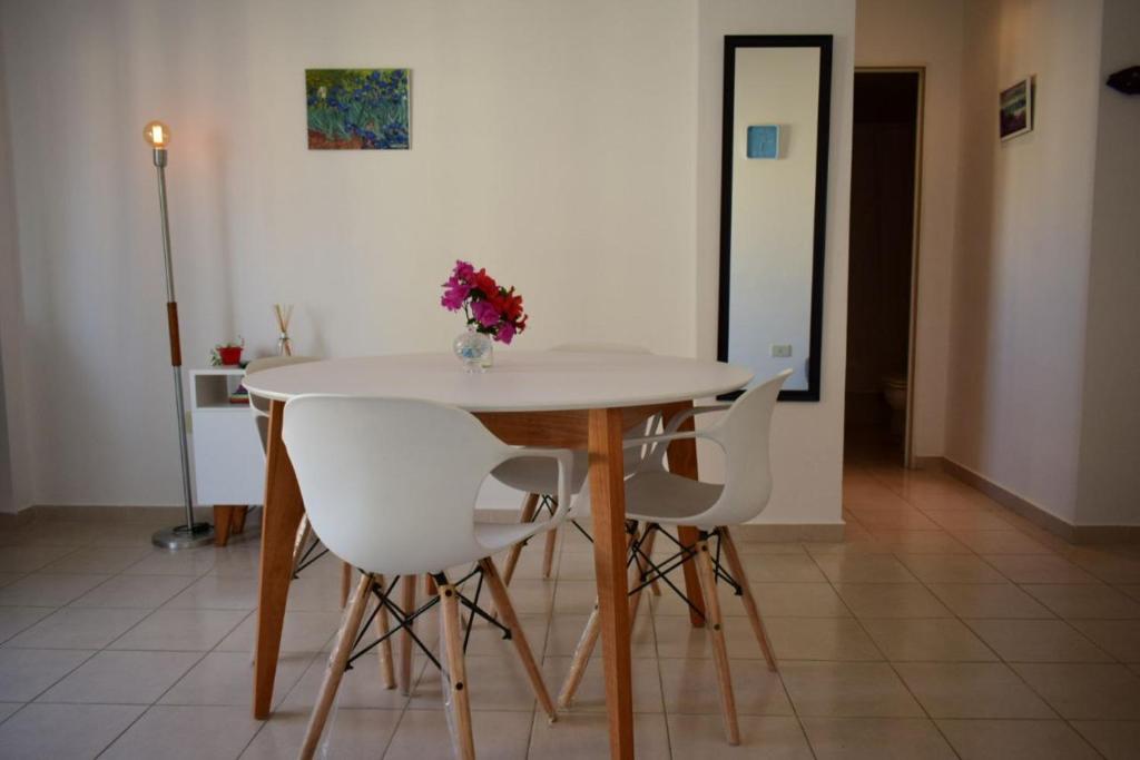 a table with white chairs and a vase of flowers on it at El Luminoso 11 in La Plata