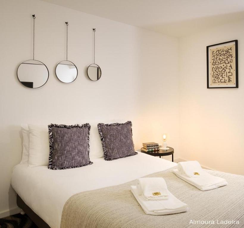 a bedroom with a bed with two mirrors on the wall at Almoura Ladeira in Évora