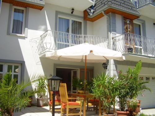 - une table et des chaises avec un parasol en face d'une maison dans l'établissement Villa Grazia, à Hévíz