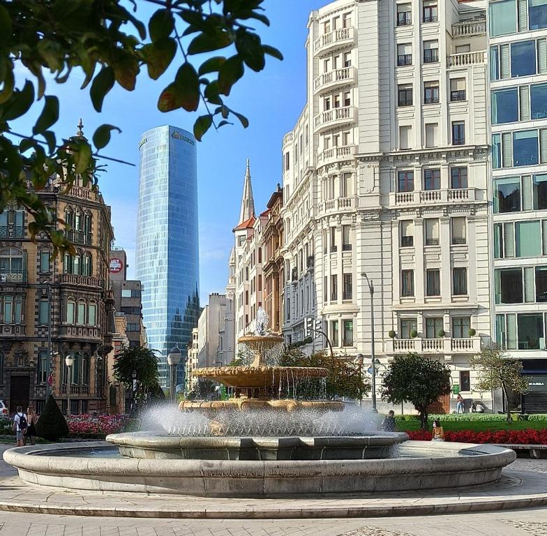 a fountain in the middle of a city with buildings at OH MY HOME BILBAO in Bilbao