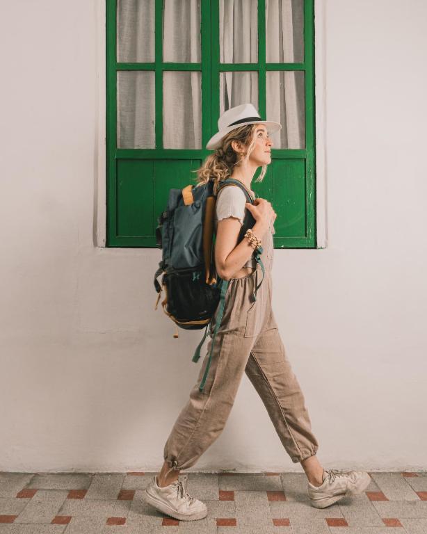 a woman with a backpack walking past a building at Wild Monkey Hostel in Cuenca