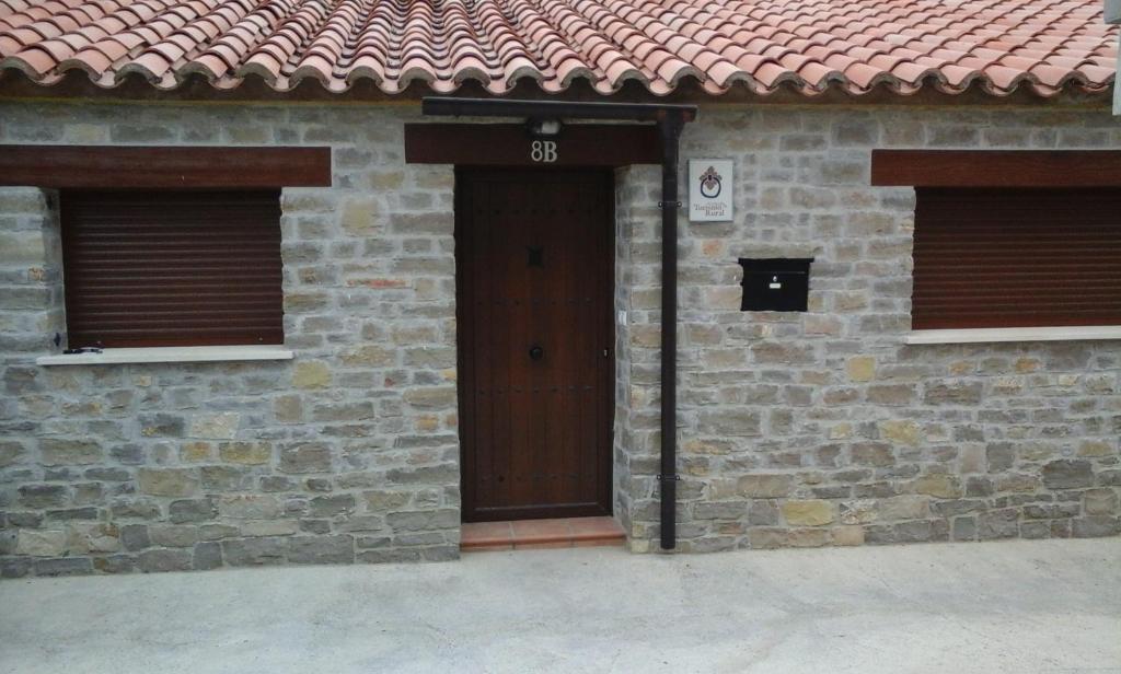 ein Backsteingebäude mit zwei Türen und einem roten Dach in der Unterkunft Casa Dinorural in El Castellar