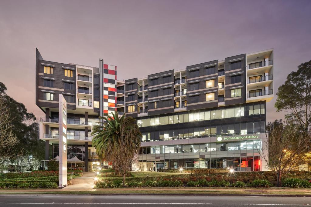 an apartment building at night with a palm tree in front at Punthill Norwest in Baulkham Hills