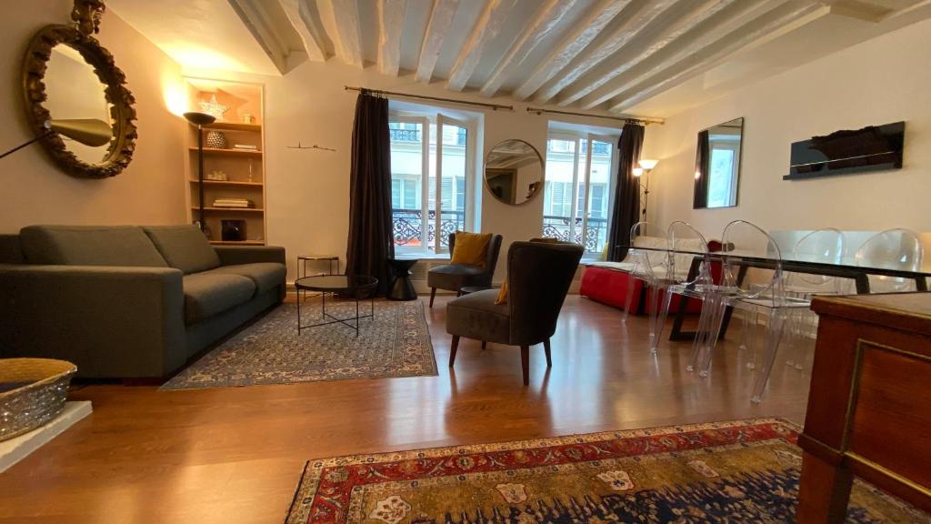 uma sala de estar com um sofá e cadeiras em Paris Coeur Saint Germain Standing em Paris