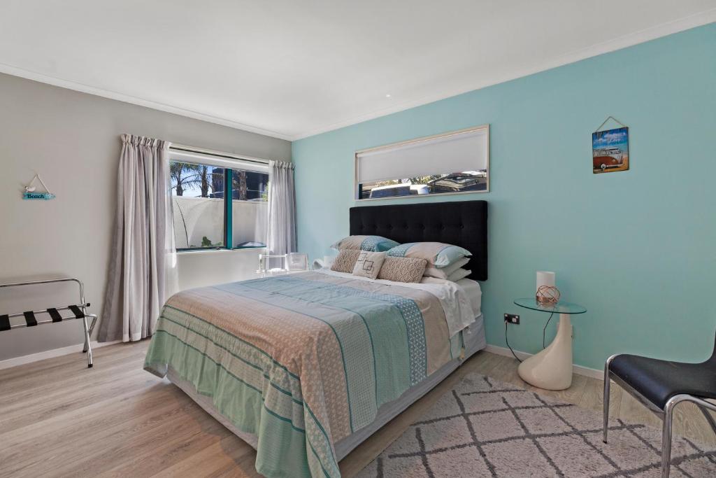 a bedroom with a large bed with blue walls at Two rooms with one queen size bed in each room one bathroom for the two rooms in Mount Maunganui