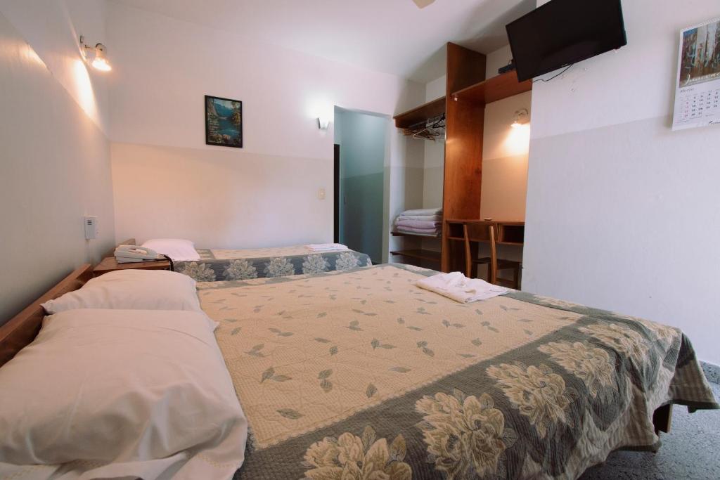 1 dormitorio con 2 camas y TV en la pared en Das Heim Hotel, en Asunción