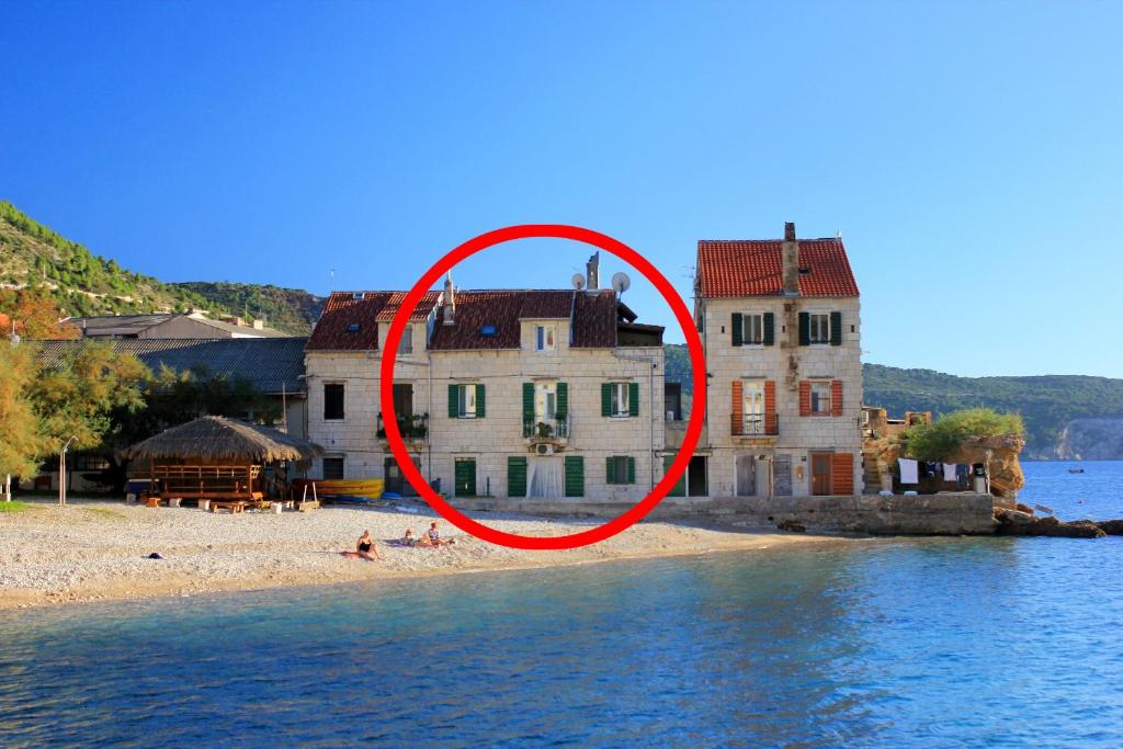 une maison sur une plage en face de l'eau dans l'établissement Apartments by the sea Komiza, Vis - 8533, à Komiža