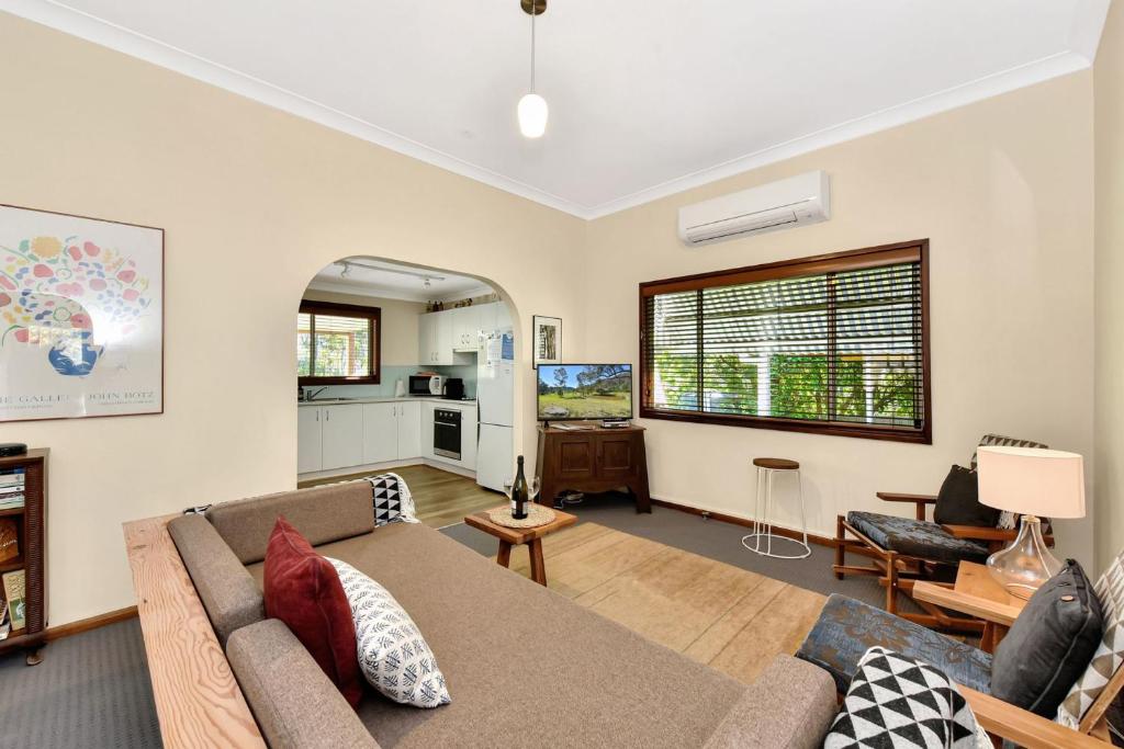 a living room with a couch and a kitchen at Summerfield Cottage Hunter Valley in Branxton