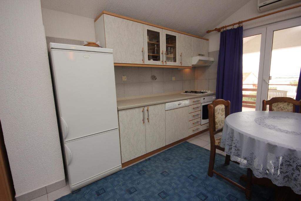 kuchnia ze stołem i białą lodówką w obiekcie Apartments with a parking space Kraj, Pasman - 8502 w mieście Tkon
