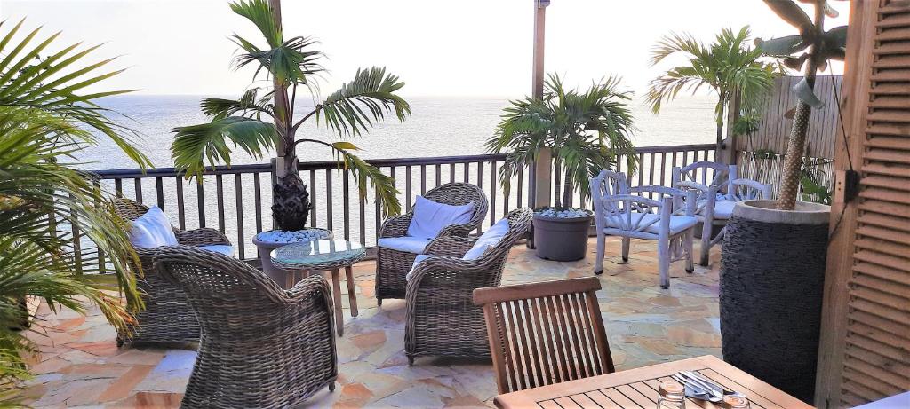 a patio with chairs and tables and the ocean at CLEMARA EVASION in Schœlcher