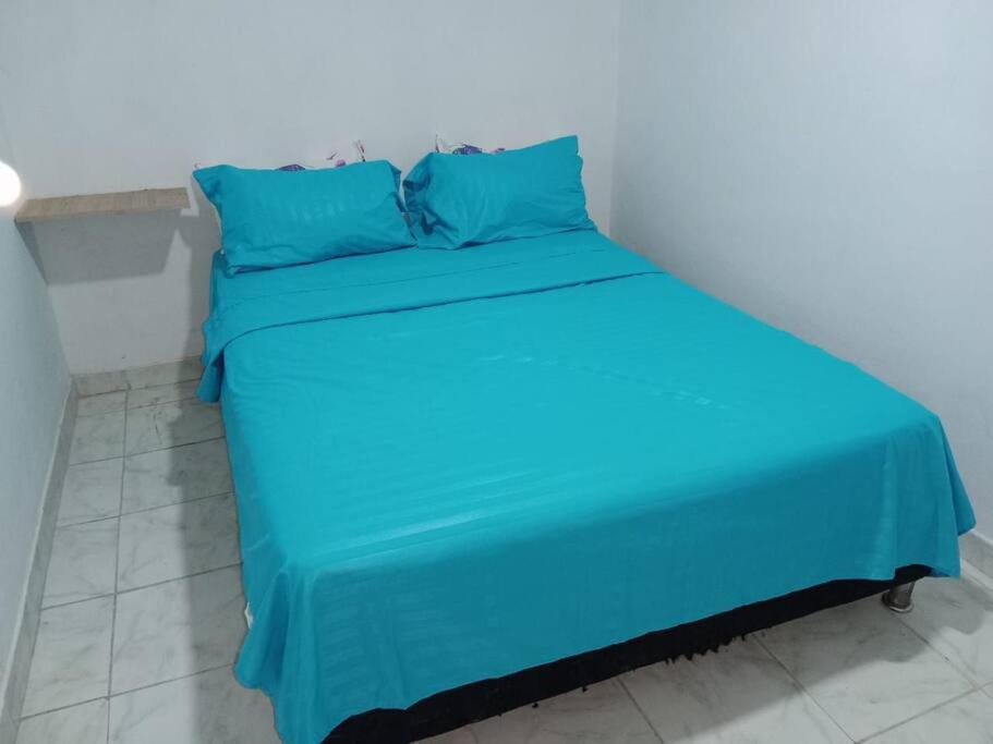 un letto con lenzuola e cuscini blu in una stanza di Hermoso apartamento independiente para pareja a Villavicencio