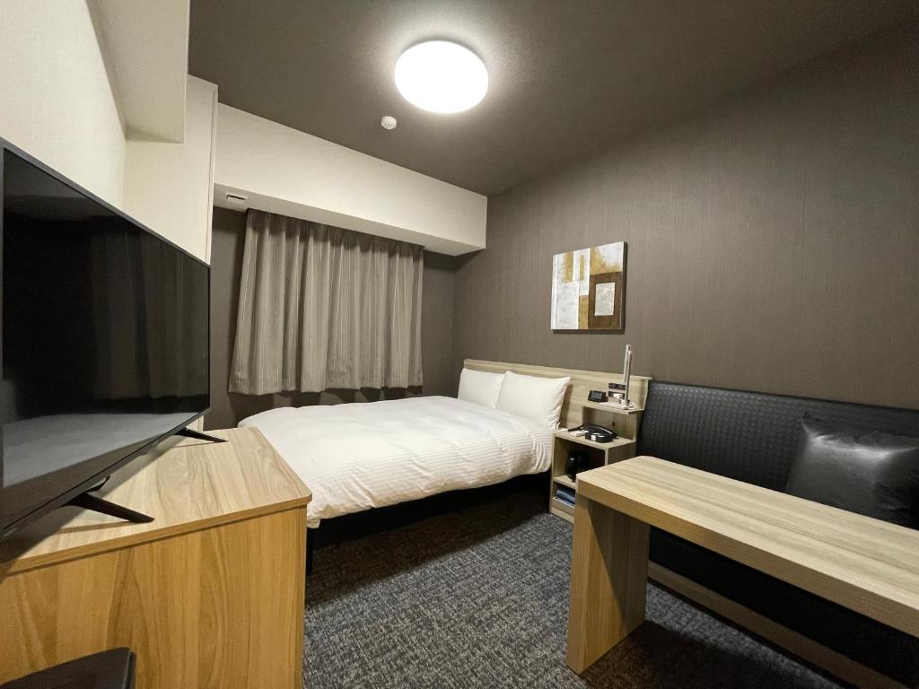 Hotel Route Inn Mitsuke -Nakanoshima Mitsuke Inter- في Mitsuke: غرفة فندقية بسرير وتلفزيون بشاشة مسطحة