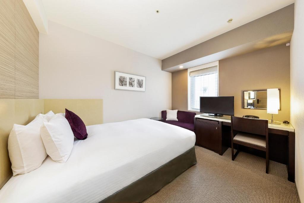una camera d'albergo con un letto e una scrivania di KOKO HOTEL Kobe Sannomiya a Kobe