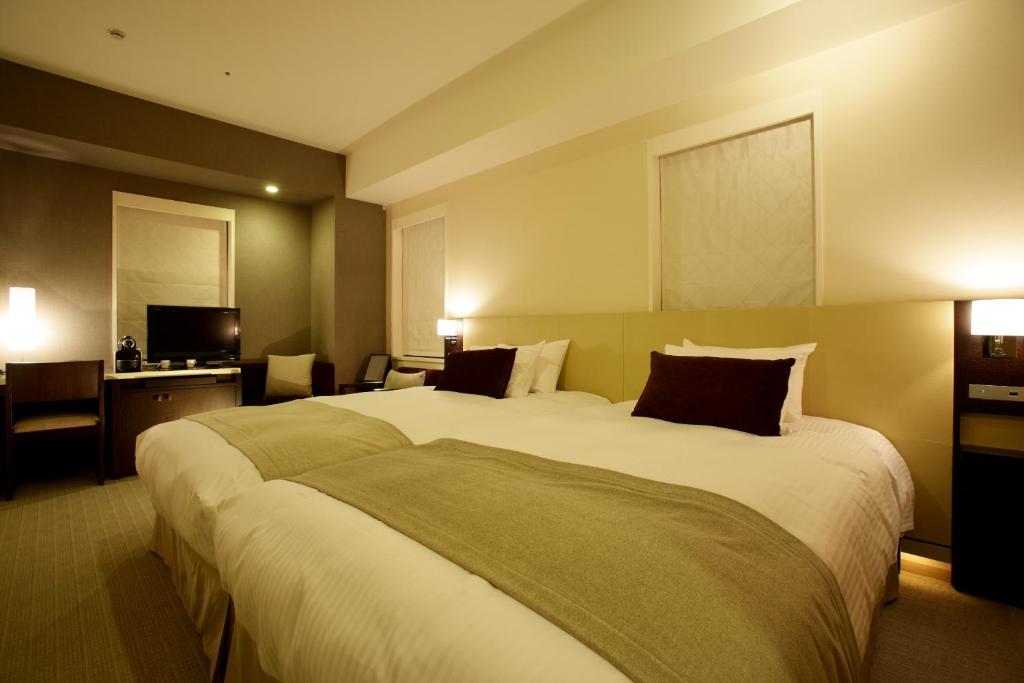 神戸市にあるKOKO HOTEL 神戸三宮の大型ベッドとテレビが備わるホテルルームです。