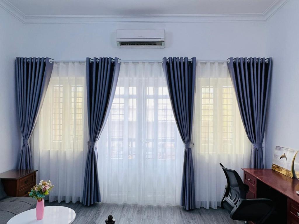 ein Wohnzimmer mit blauen und weißen Vorhängen in der Unterkunft MINA HOUSE Airport Apartment in Ho-Chi-Minh-Stadt