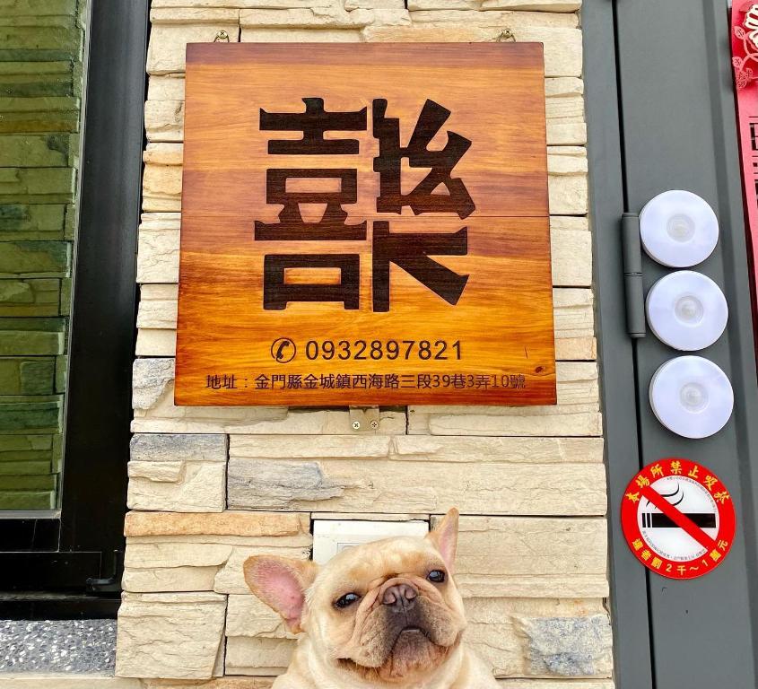 a dog is sitting in front of a sign at 金門禧樂民宿 in Shan-ch'ien