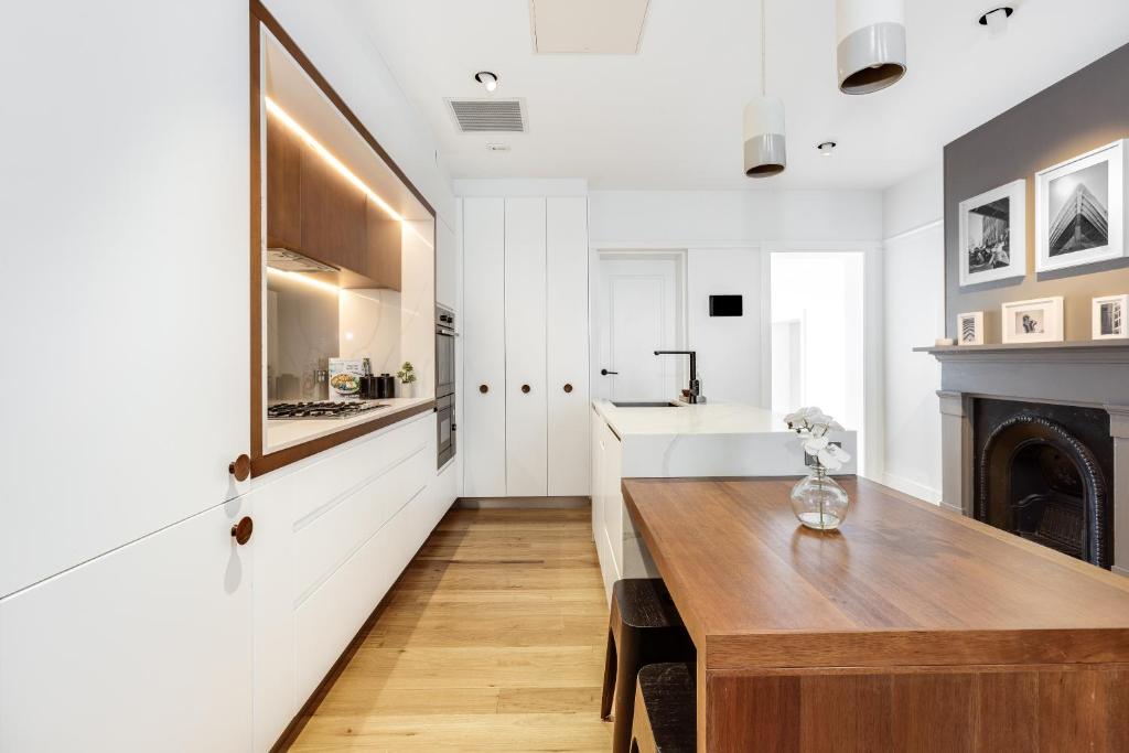 a kitchen with a wooden table and a fireplace at Barangaroo Park Apartments by Urban Rest in Sydney